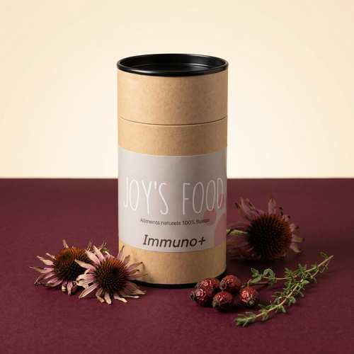 Pot en carton kraft Joy's Food Immuno+ avec fleurs d'échinacée, baies d'églantier et thym sur fond bordeaux premium.